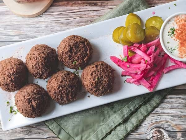 Falafel served with pickled vegetables, olives, and creamy dipping sauce.