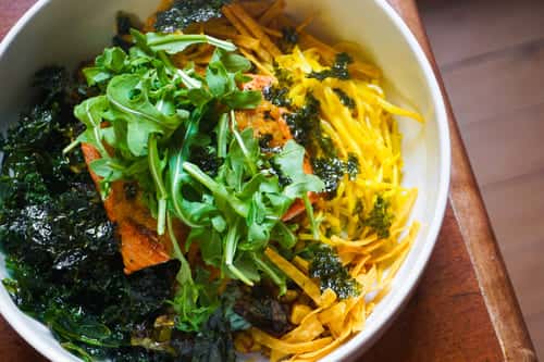 Colorful poke bowl with marinated tofu, shredded vegetables, seaweed, and arugula over rice, capturing vibrant, health-focused dining.