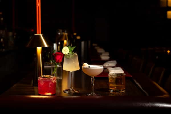 Drinks lined up on a bar table in dark, moody lighting