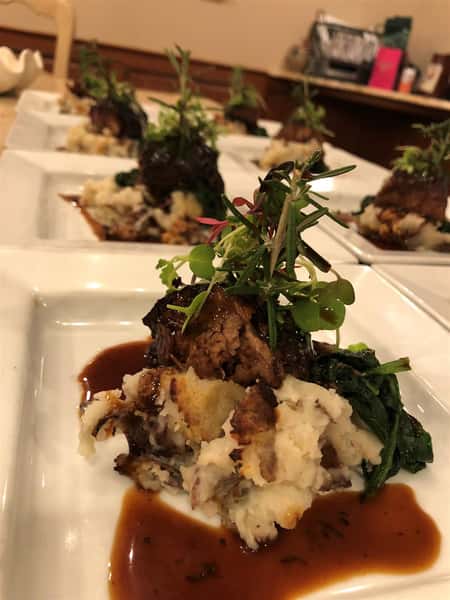 mashed potatoes and gravy with a garnish on a white plate with many others in the background