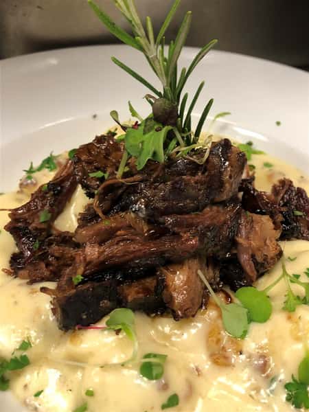 slices of meat on a creamy sauce on a white plate