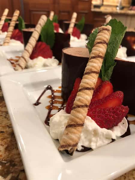 a chocolate truffle dessert on a plate with a sliced strawberry and whipped cream on a plate