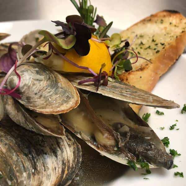 Steamed clams with herbs over toasted garlic bread