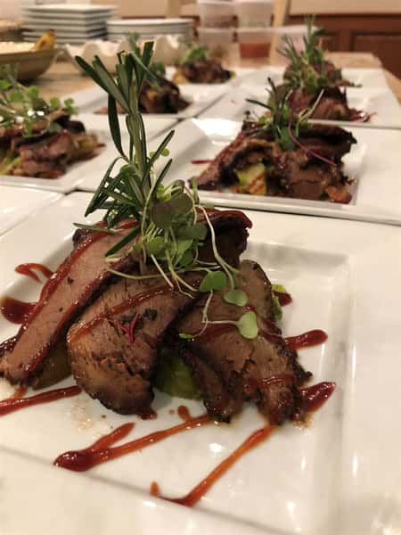 sweet potato and roast beef with gravy on a plate and garnished with many others in the background