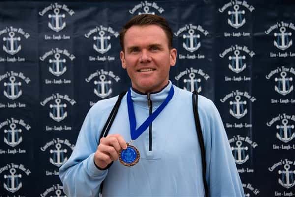man with blue medal