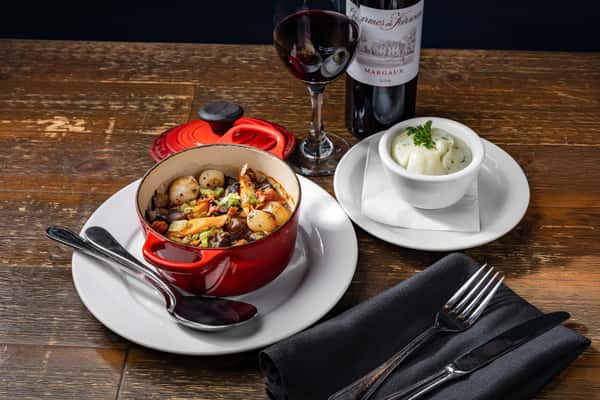 boeuf bourguignon with a side of mashed potatoes and a glass or red wine