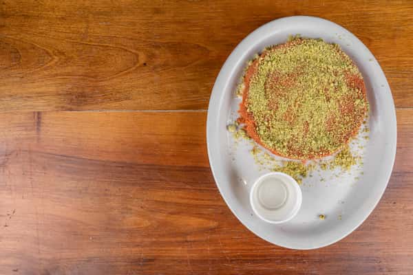 Traditional Middle Eastern knafa dessert topped generously with crushed pistachios.