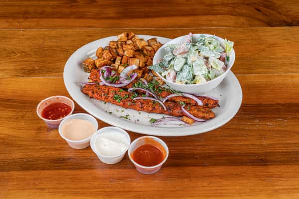 Chicken kafta plate with seasoned grilled meat, fresh salad, vegetables, and house sauces.