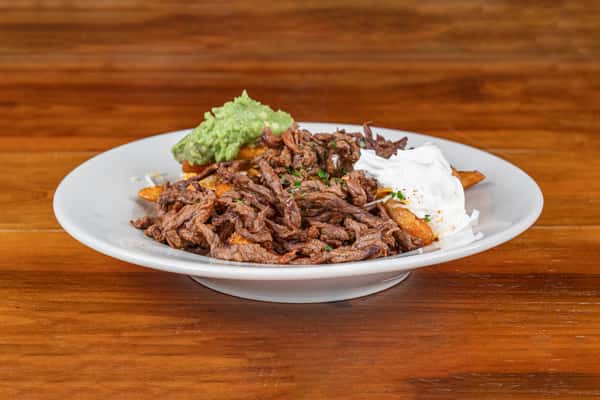 Loaded beef fajita fries topped with grilled beef, guacamole, and sour cream.