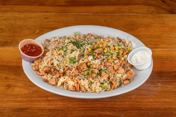 Savory fried rice with chicken, vegetables, herbs, and a side of creamy sauce.