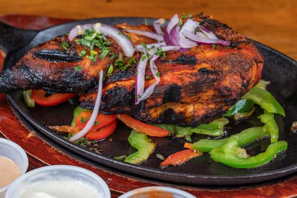 Grilled half chicken with peppers and onions served sizzling with house sauces.