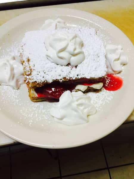 Bread topped with powdered sugar, fruit, whipped cream