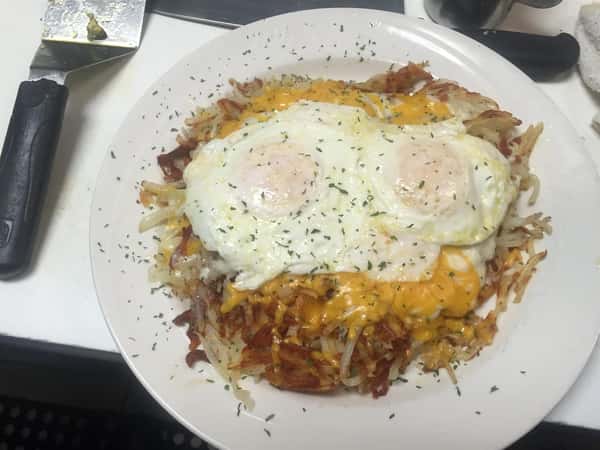 Over Medium Eggs over hashbrowns and cheese on a white plate
