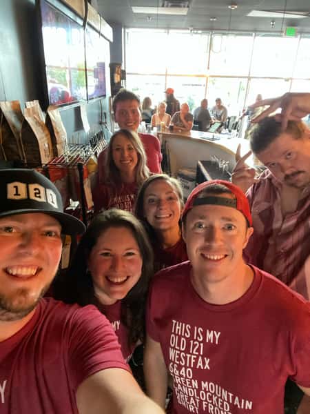 Smiling group of staff and friends in matching red shirts inside Old 121 Brewhouse during a lively event.