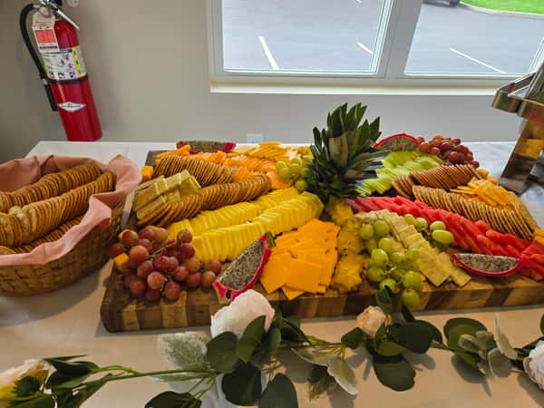 A vibrant catering display featuring an assortment of cheeses, fruits, and crackers, arranged on a wooden board with a decorative pineapple centerpiece.A vibrant catering display featuring an assortment of cheeses, fruits, and crackers, arranged on a wooden board with a decorative pineapple centerpiece.