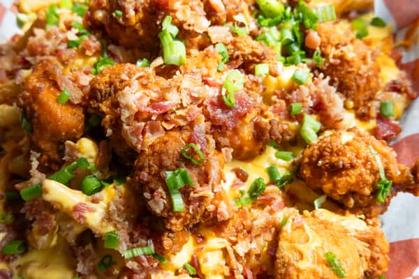 loaded fries topped with crispy fried chicken, melted cheese, bacon bits, and green onions