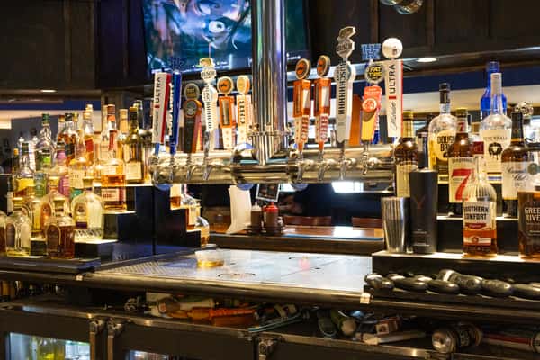 sports bar beer taps and liquor selection with multiple draft handles and TVs in a casual bar setting