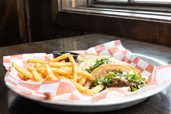 street tacos with chopped beef, onions, cilantro, and lime served with seasoned French fries