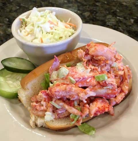Lobster roll with side of colesale and pickles