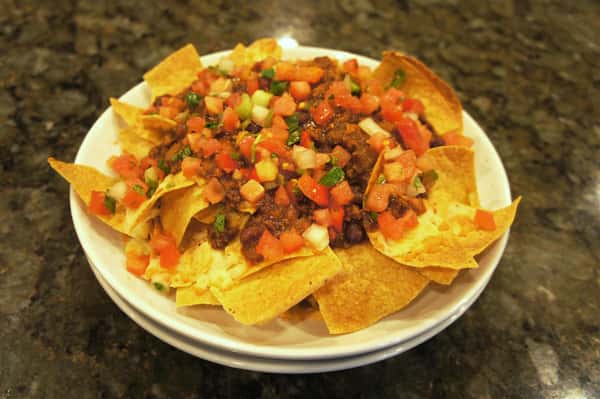Plate of nachos with diced tomatoes and chopped meat