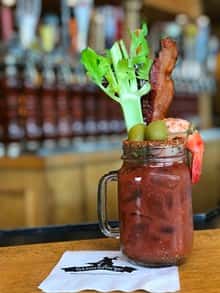 Bloody mary in mason jar with bacon, olives,and celary