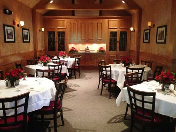 Dining room with empty white tables with red flowers