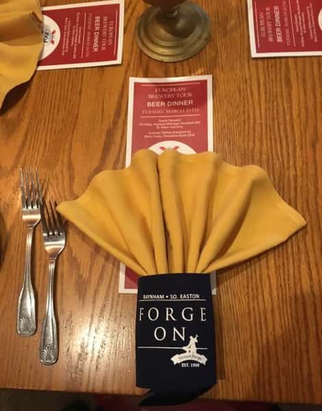 Wood table setting with yellow napkin and beer