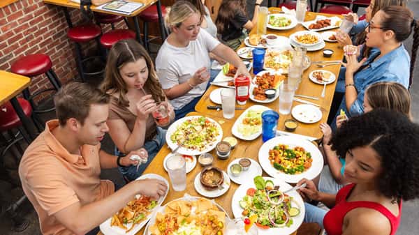 Group of people celebrating with a table full of food and drinks at Carolina Ale House