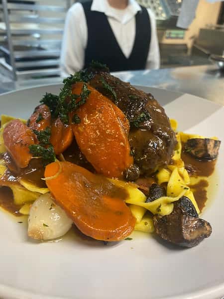 Braised beef short rib over tagliatelle pasta with carrots, pearl onions, mushrooms, and rich brown sauce.