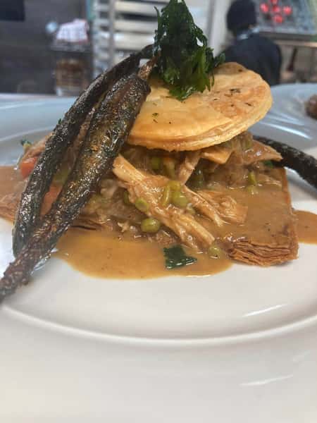 Shredded chicken vol-au-vent in creamy sauce, topped with a golden pastry lid and garnished with crispy fried okra.