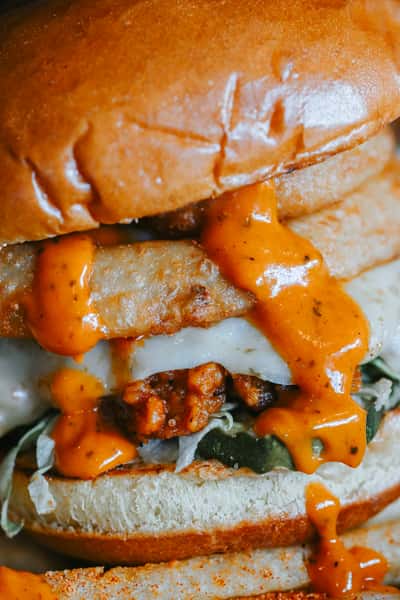 Hot honey chicken sandwich stacked with crispy chicken, melted cheese, and spicy honey sauce on a toasted bun.