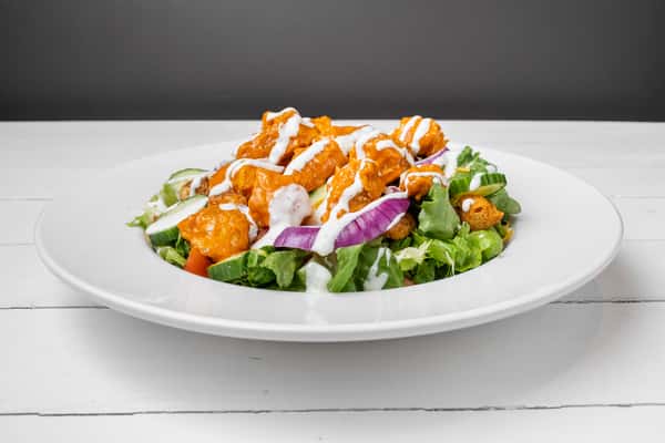 Fresh garden salad topped with crispy buffalo chicken tenders, shredded cheese, red onions, and ranch dressing at Dick's Wings & Grill.