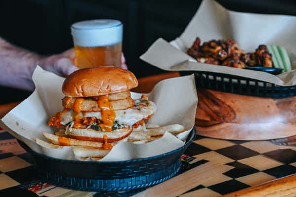 Hot honey chicken sandwich served with fries, featuring crispy chicken and sweet heat sauce.