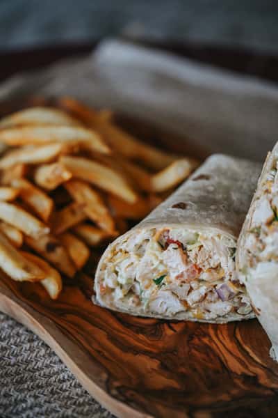 Chicken tender wrap filled with crispy chicken, fresh vegetables, and creamy dressing, served with fries.