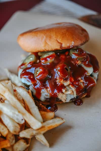 Spicy Cowboy Burger topped with barbecue sauce, melted cheese, crispy bacon, and onion straws on a toasted bun.