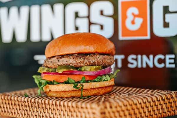 Signature beef burger with crisp lettuce, tomato, onion, and melted cheese on a soft brioche bun.