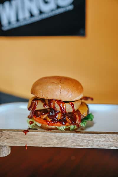 Signature BBQ bacon cheeseburger stacked with onion straws and barbecue sauce on a soft brioche bun.
