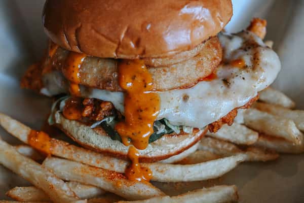 Close-up of a hot honey chicken sandwich loaded with crispy chicken, melted cheese, and signature sauce.