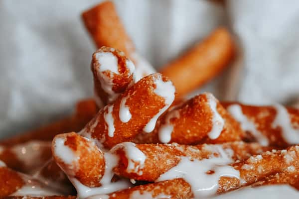 Funnel cake fries dusted with powdered sugar and drizzled with sweet icing for a carnival-style dessert.