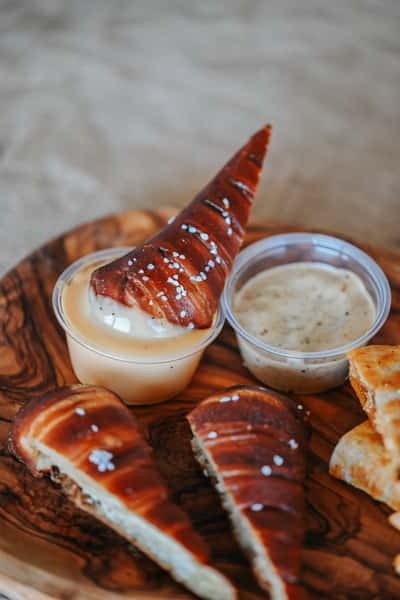 Freshly baked pretzel bites with golden brown crust served alongside savory dipping sauces.