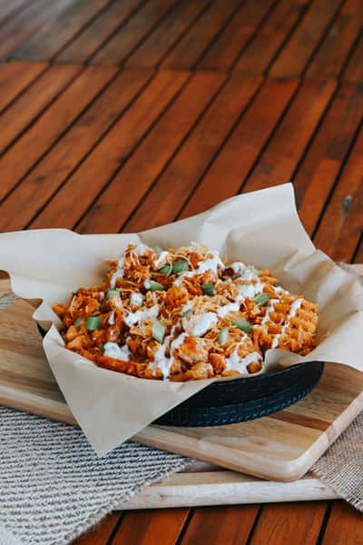 Ultimate loaded waffle fries covered with seasoned chicken, melted cheese, ranch dressing, and green onion garnish.