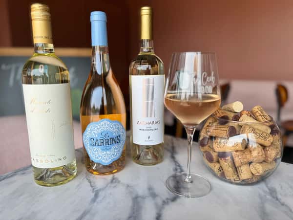 Table of wine bottles and one of them has been poured into a wine glass