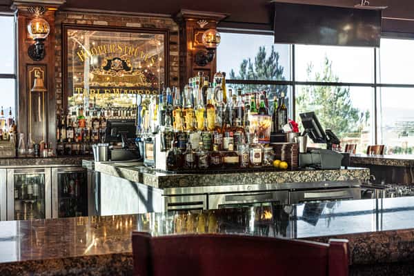 upscale restaurant bar interior with illuminated liquor shelves, mirrored accents, and elegant lounge seating