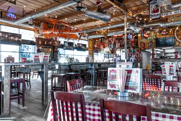 rustic restaurant dining room with checkered tablecloths, exposed wood beams, and lively bar seating