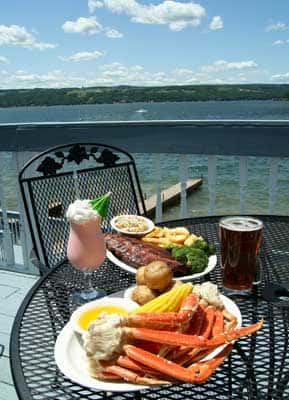 Crab legs with corn on the cob and potatoes in front of a river.