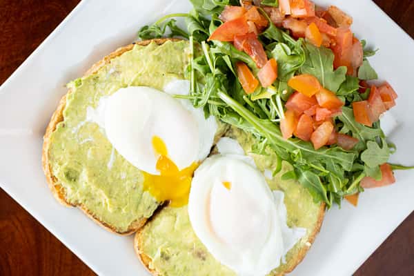 Avocado Toast: Toasted bread topped with mashed avocado, fresh diced tomatoes, and two soft-poached eggs.