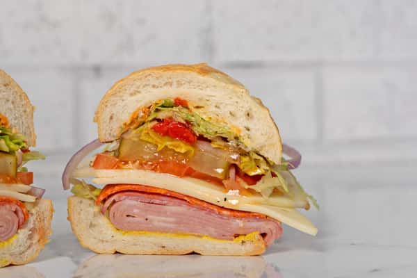 close up of Italian hoagie with layered deli meats, cheese, lettuce, tomato, and dressing