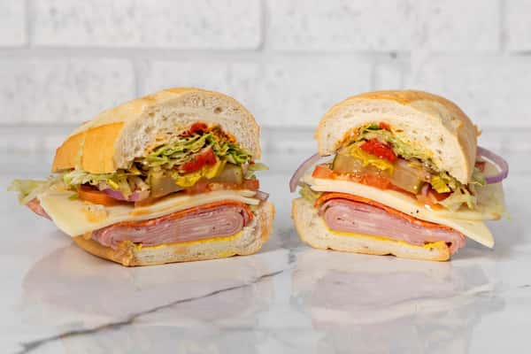 Italian sub sandwich with salami, ham, provolone, lettuce, tomato, and peppers on fresh bread