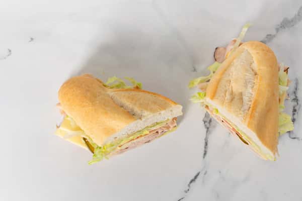 turkey and cheese sub sandwich cut in halves with lettuce on a soft hoagie roll