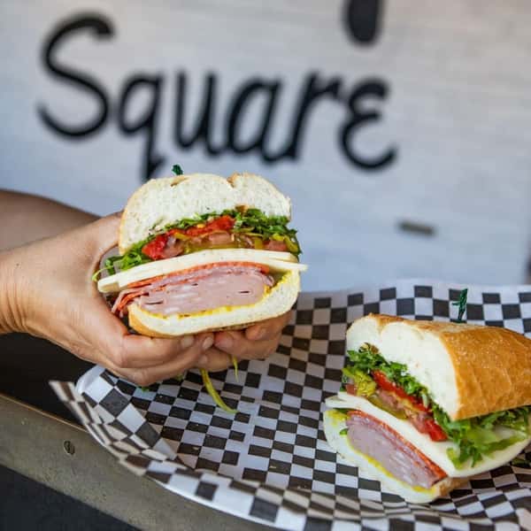 Deli sandwich cut in half to show the layers of meat and toppings